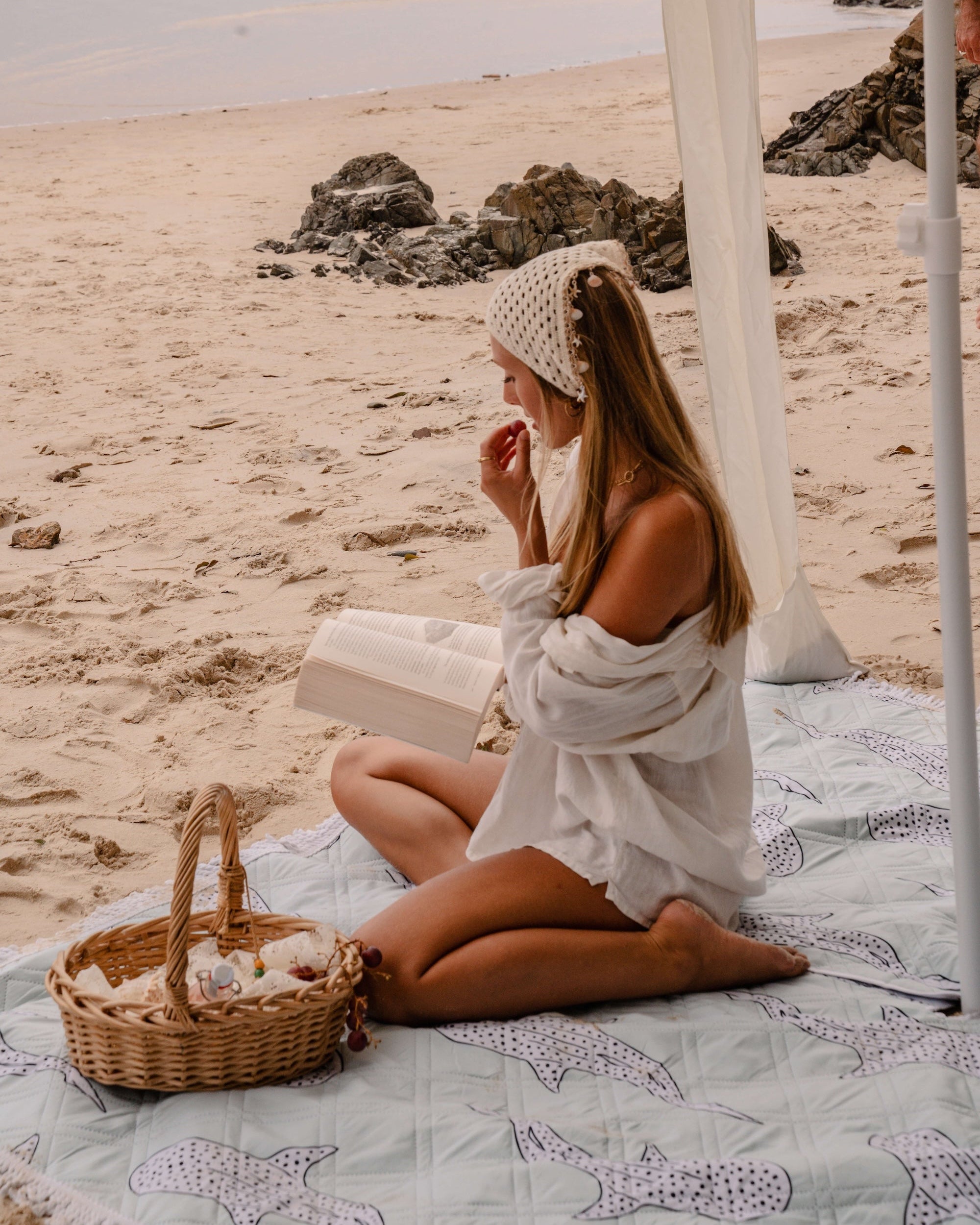 woman on a beach blanket reading a book