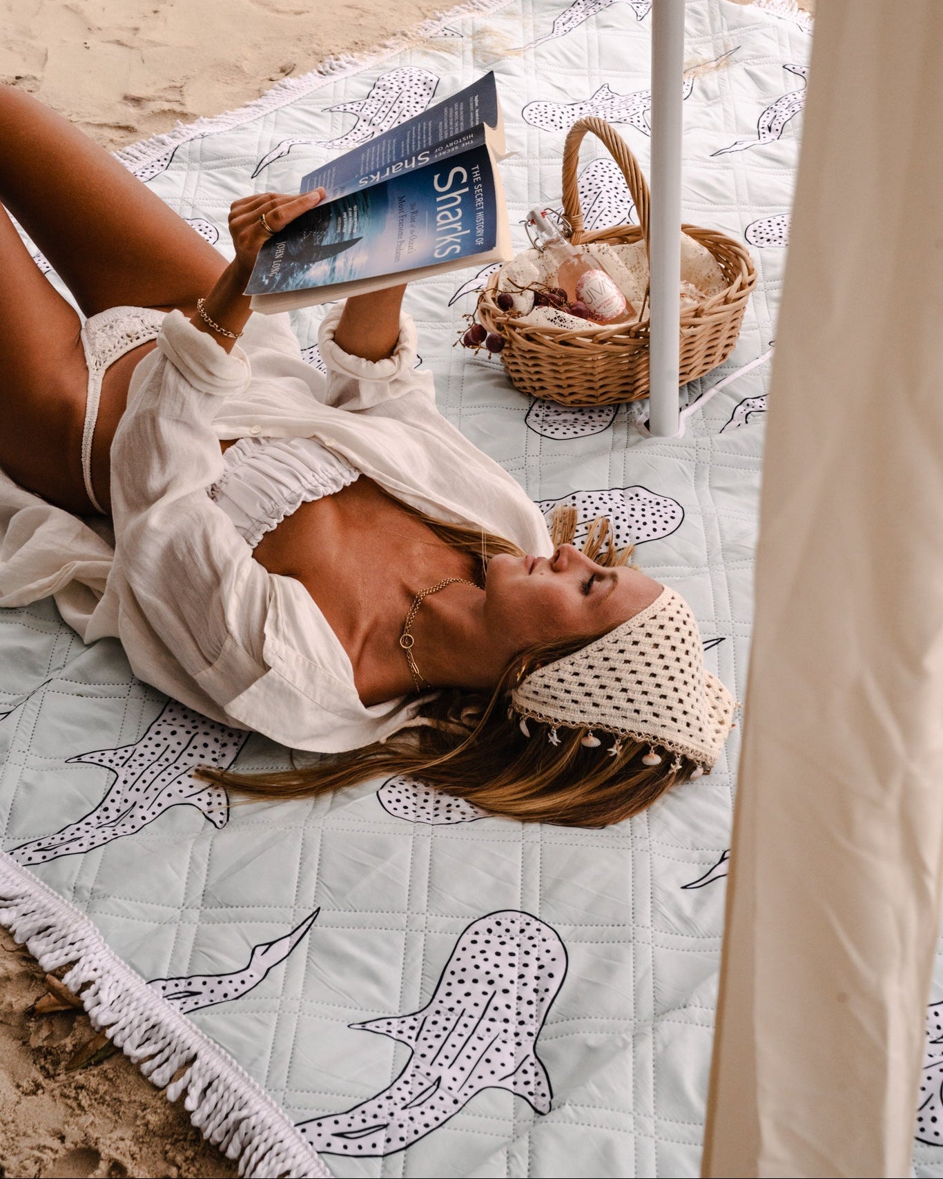 Woman lying and reading a book on a beach towel